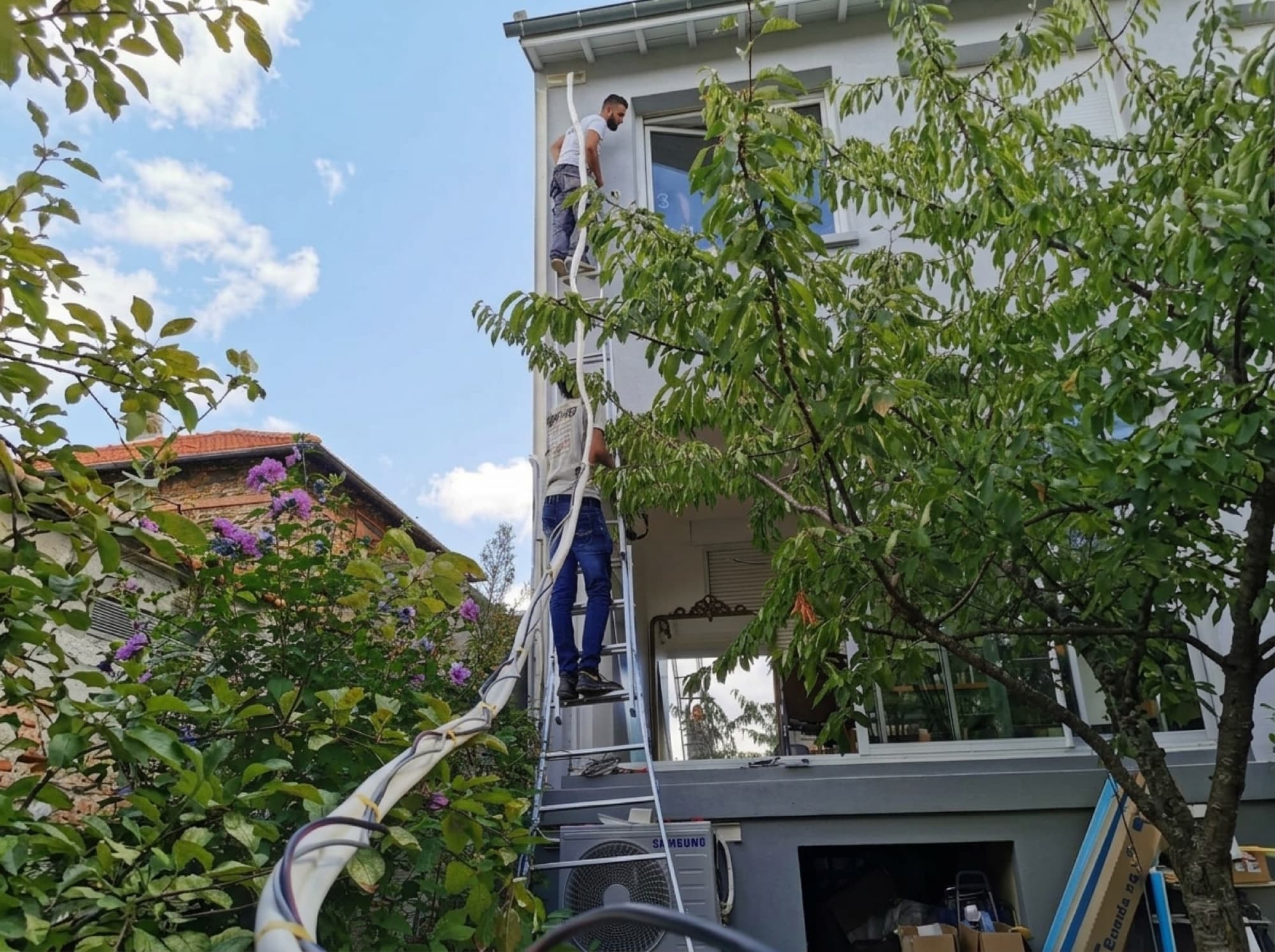 Installation d'une climatisation en façade depuis une échelle