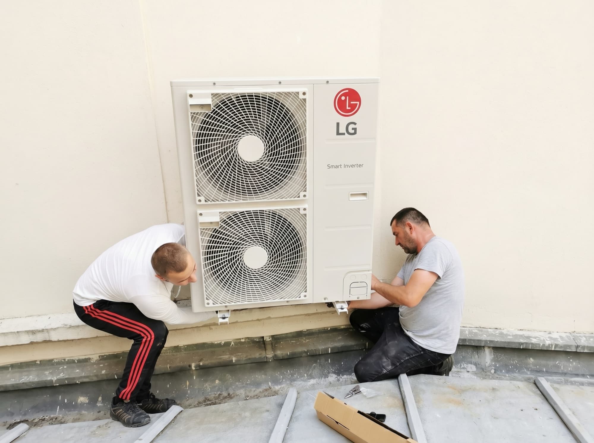 Pose d'un groupe extérieur de climatisation par deux techniciens